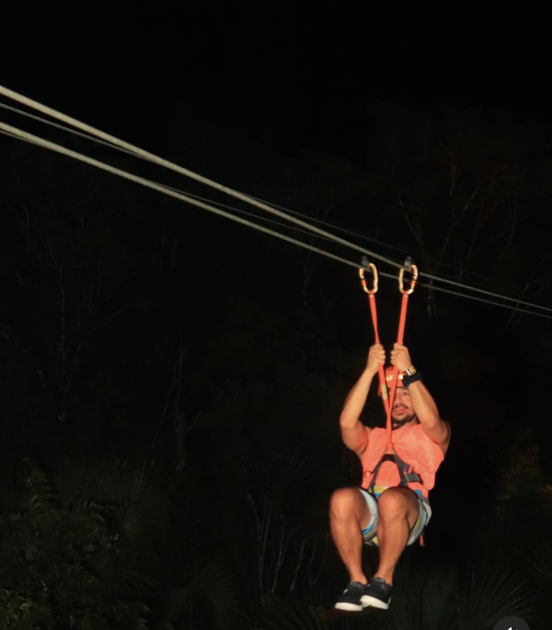 Adrian flying down a zipline through the jungle at night